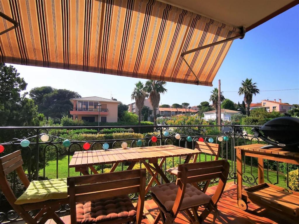 un patio avec une table et des chaises sur un balcon dans l'établissement Le Cocon vert T2 St Aygulf à 30m de la mer, à Saint-Aygulf