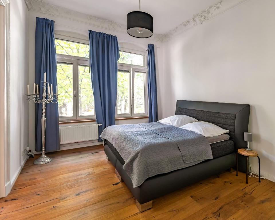 奧爾登堡的住宿－Modern 6 bathroom villa in the city，一间卧室配有一张带蓝色窗帘的床,铺有木地板