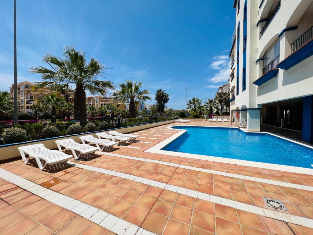 a swimming pool with lounge chairs next to a building at Marina 4 apartment in Huelva