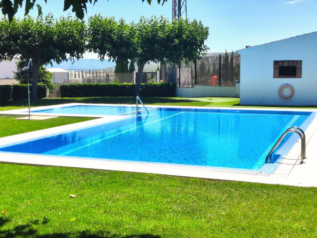 una piscina blu in un cortile con prato di Casa Rural Vistaverde a Luque