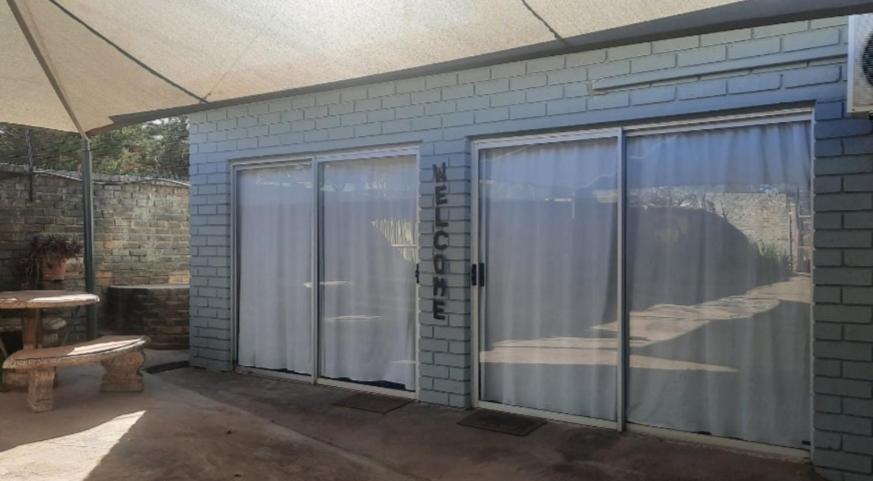 un patio con puertas correderas de cristal y un banco en Kalahari Kaja en Kuruman