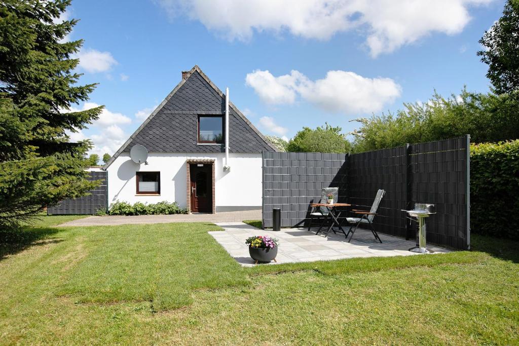 una pequeña casa blanca con una valla negra en An der Rehkoppel, en Boren