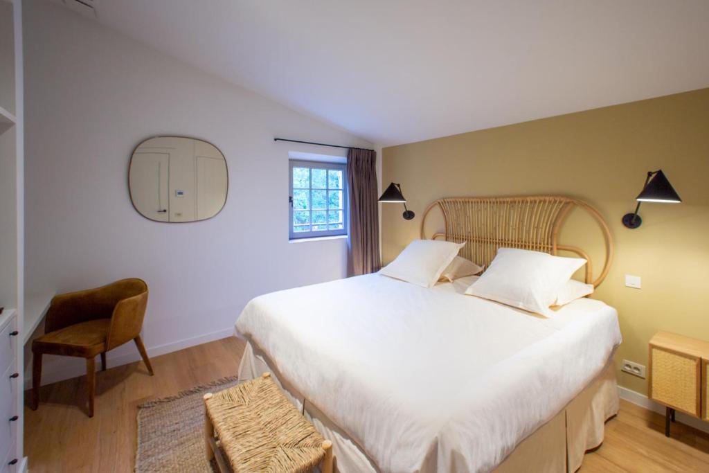 a bedroom with a large white bed and a chair at Bastide de la Bergerie d&#39;Aquino in Tourves