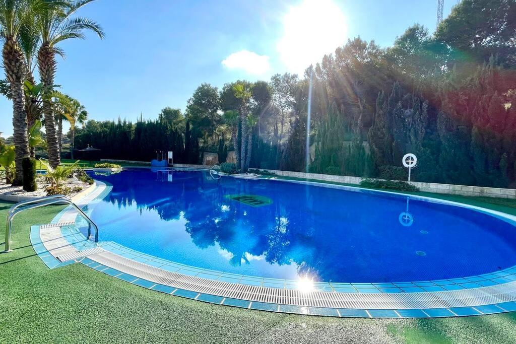 uma grande piscina num quintal com árvores em 12-Apartamento en la playa Piscina em Alicante