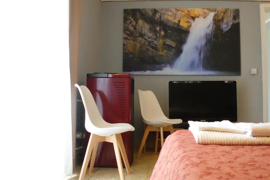 een slaapkamer met een bed en 2 stoelen en een televisie bij Exclusive Apartments in center in Mistretta