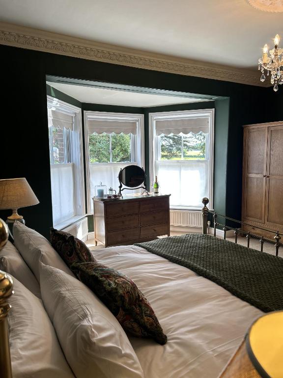 a bedroom with a large bed and two windows at The Lodge at Salhouse in Norwich