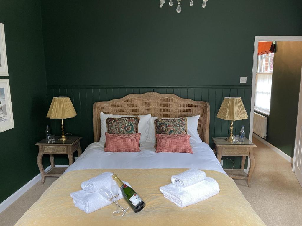 a bed with two towels and a bottle of wine on it at The Lodge at Salhouse in Norwich