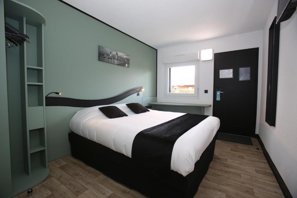 ein Schlafzimmer mit einem großen Bett und einem Fenster in der Unterkunft Enzo Hotels Chartres Mainvilliers by Kyriad Direct in Chartres