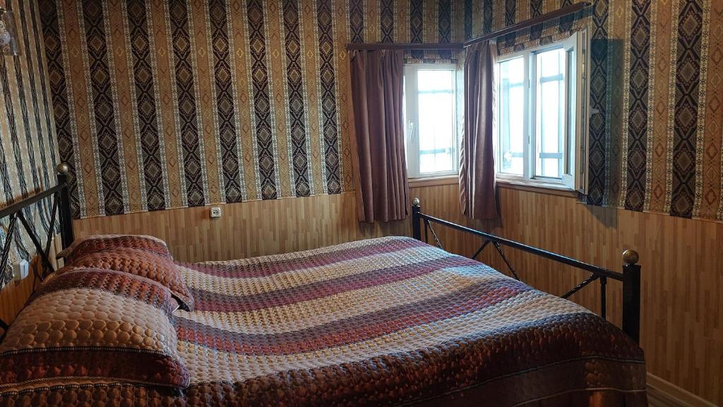 a bedroom with a bed with a striped comforter and a window at Sevan - Tsovazard Beach House in Tsovazard