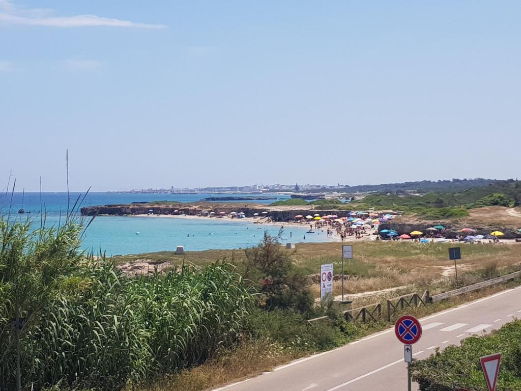 a road next to a beach with people in the water at Villetta Hakuna Matata in Torre Specchia Ruggeri