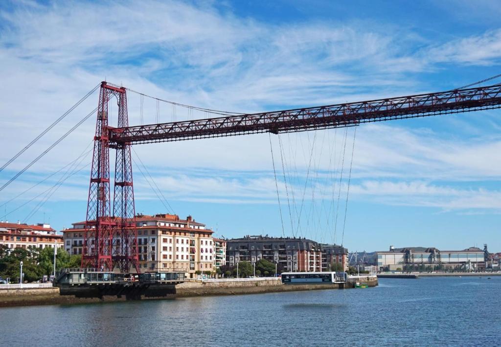 un gran puente rojo sobre un río con edificios en Family Apartment / Apartamento familiar Getxo, en Getxo