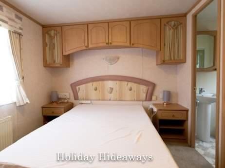 a bedroom with a large white bed and wooden cabinets at Rockley Park, Gorse Hill 38 in Lytchett Minster
