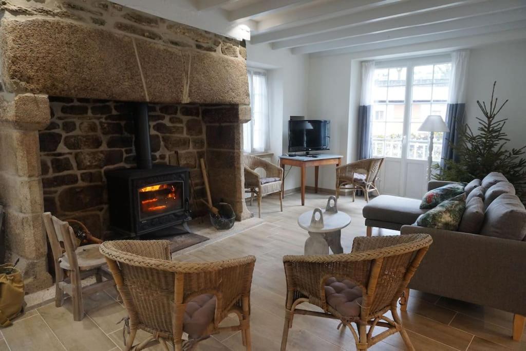 uma sala de estar com lareira e um sofá e cadeiras em Le clos du 10 em Treignac