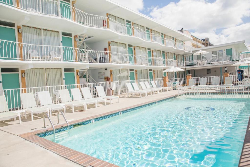 a pool in front of a hotel with chairs and a building at Biscayne Family Resort in Wildwood Crest