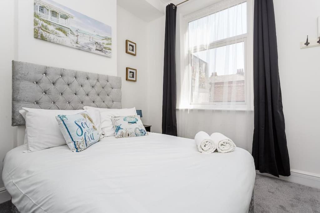 Un dormitorio con una cama blanca con dos zapatos. en Dockyard Dreams en Portsmouth