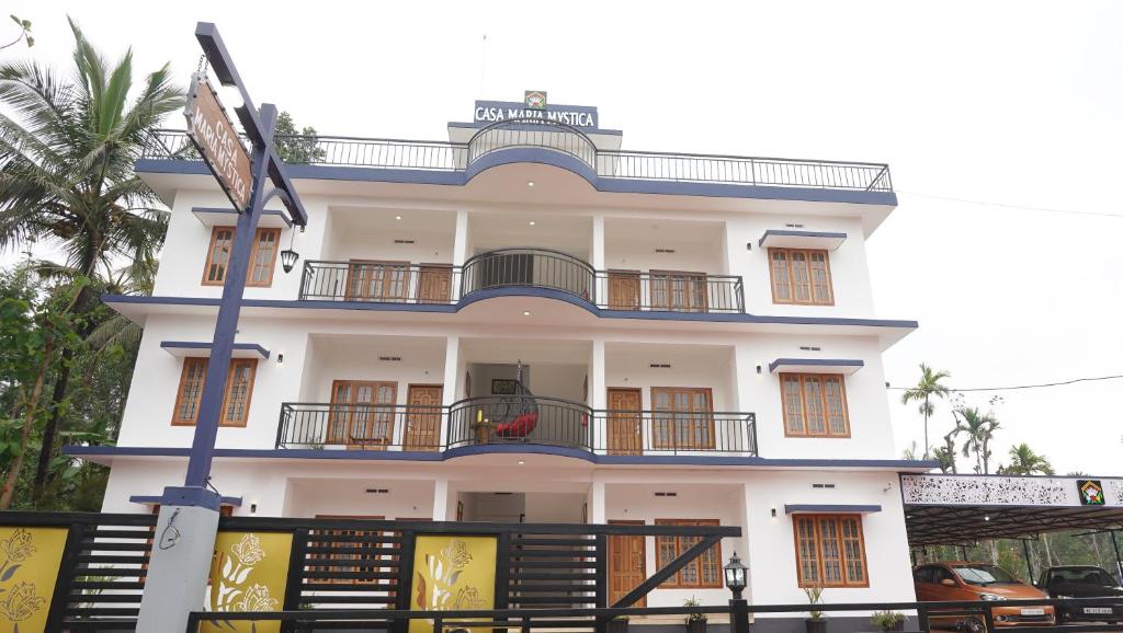 a large white building with balconies and a pole at Casa Maria Mystica apartments, Mananthavady, Wayanad in Mānantoddy