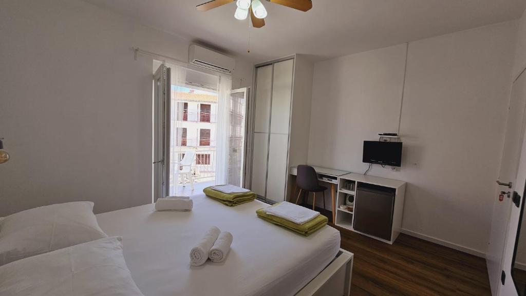 a white bedroom with a bed and a television at Vinko rooms in Primošten