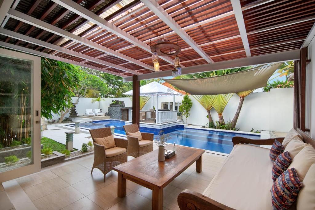 een woonkamer buiten met een bank en een tafel bij 3BR Villa Shree Canggu beach - Parking, Wifi & Pool in Canggu