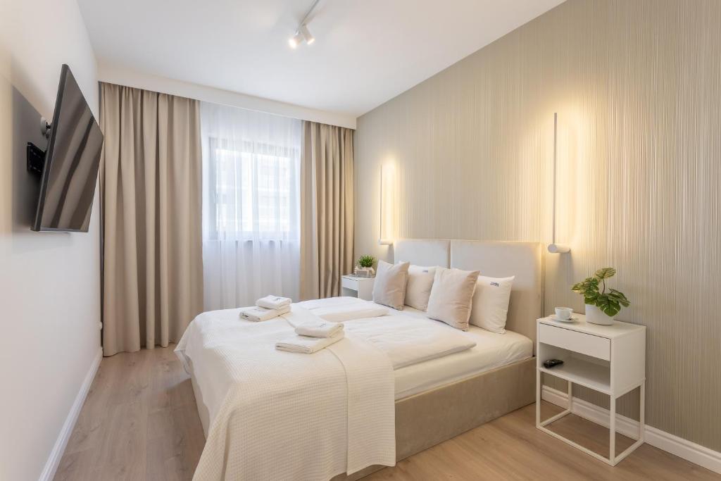 ein Schlafzimmer mit einem großen weißen Bett und einem TV in der Unterkunft Ambria Apartments Platan Complex in Świnoujście
