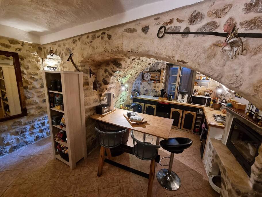 a kitchen with a table and a stone wall at Typique maison de village in Peille