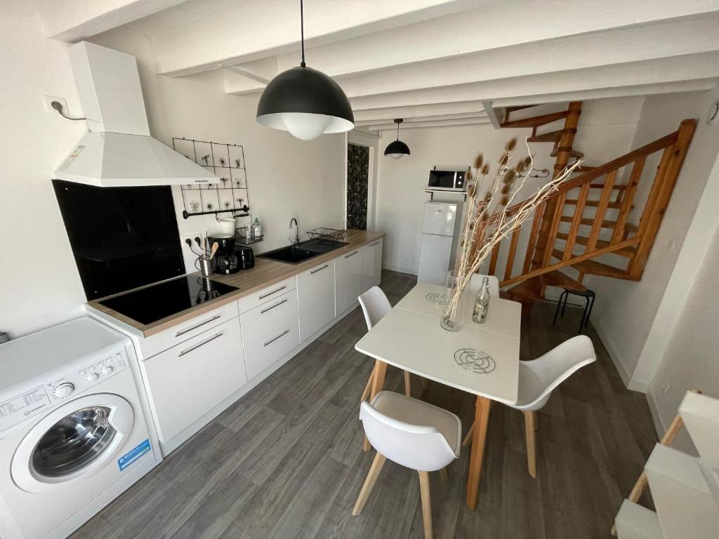 a kitchen with a table and a laundry room at Petite maison centre Bourg, 20 min du Puy du Fou in Pouzauges