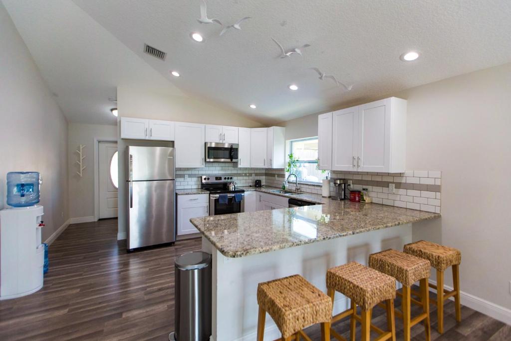 a kitchen with white cabinets and a large island with bar stools at New Construction - Pristine Home - Great Location in Stuart