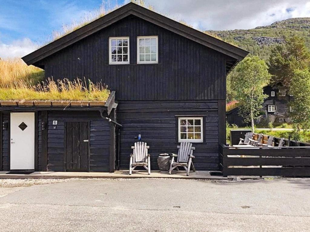 dos sillas sentadas fuera de un edificio negro con techo de hierba en Holiday home HOVDEN II, en Hovden