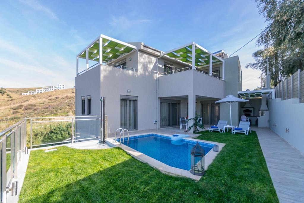 a villa with a swimming pool and a yard at Ilianthos in Panormos Rethymno