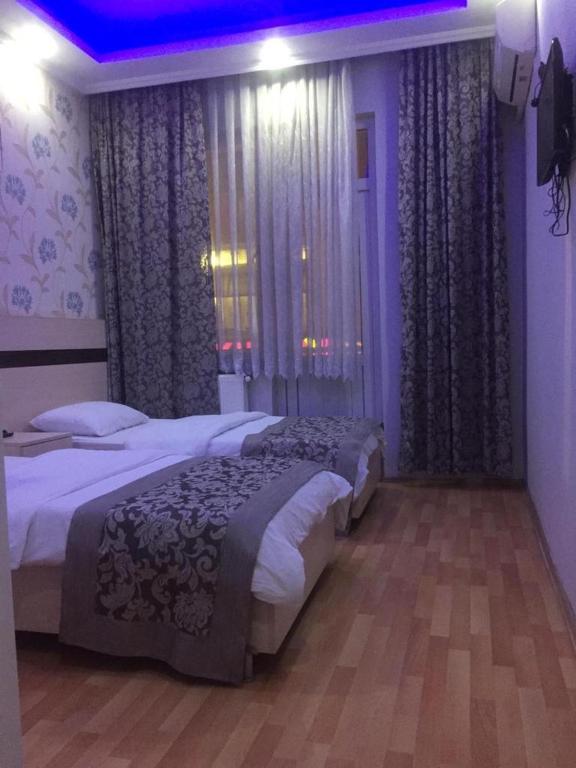 2 camas en un dormitorio con luces y cortinas púrpuras en OTEL BURAK, en Unye