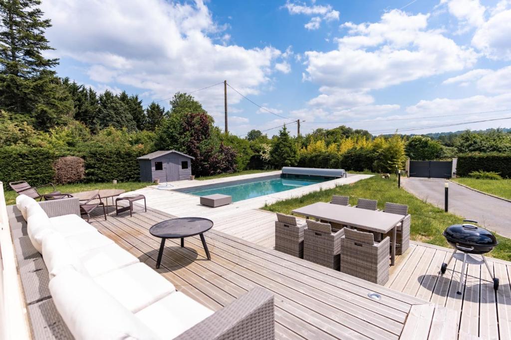 a backyard with a pool and a wooden deck at Property with heated pool near Deauville in Saint-Étienne-la-Thillaye