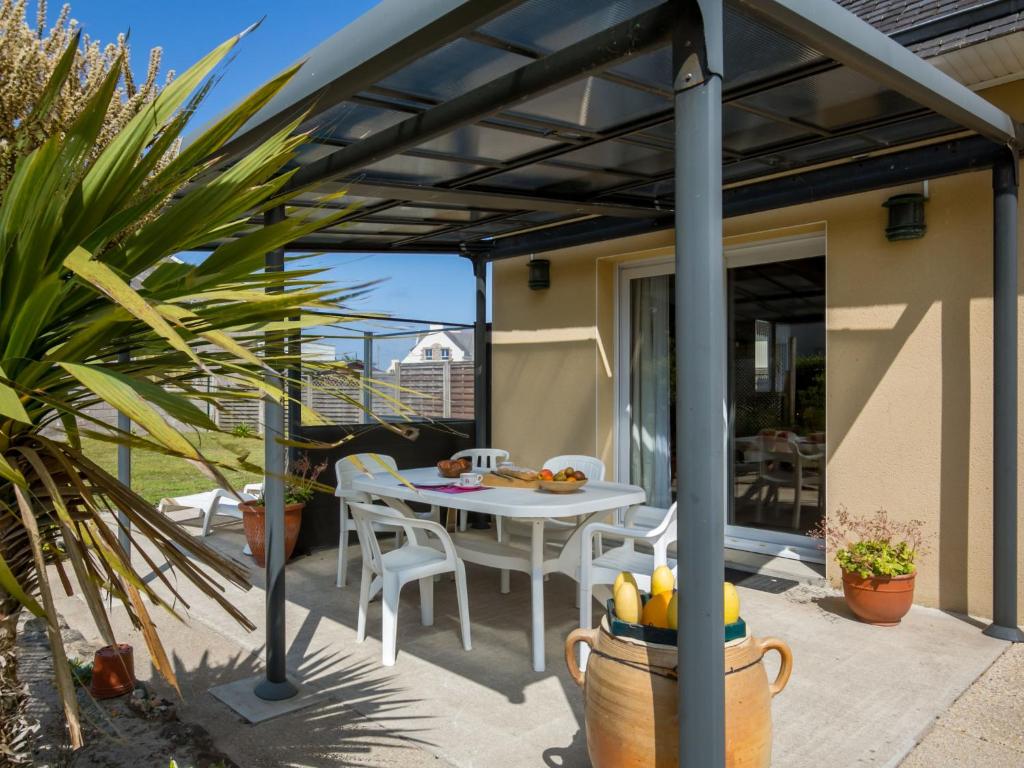 een terras met een tafel en stoelen onder een pergola bij Holiday Home Rève de Plage by Interhome in Santec