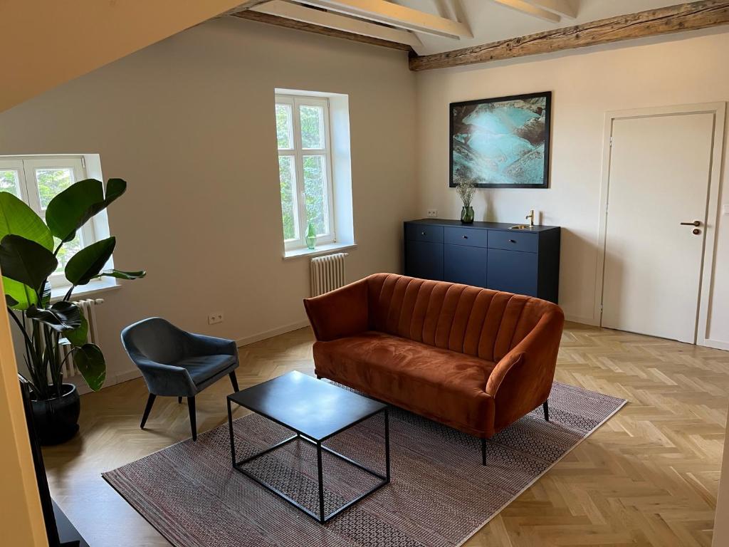 een woonkamer met een leren bank en een stoel bij APARTAMENT CENTRUM MIASTA PARKING in Nowy Sącz