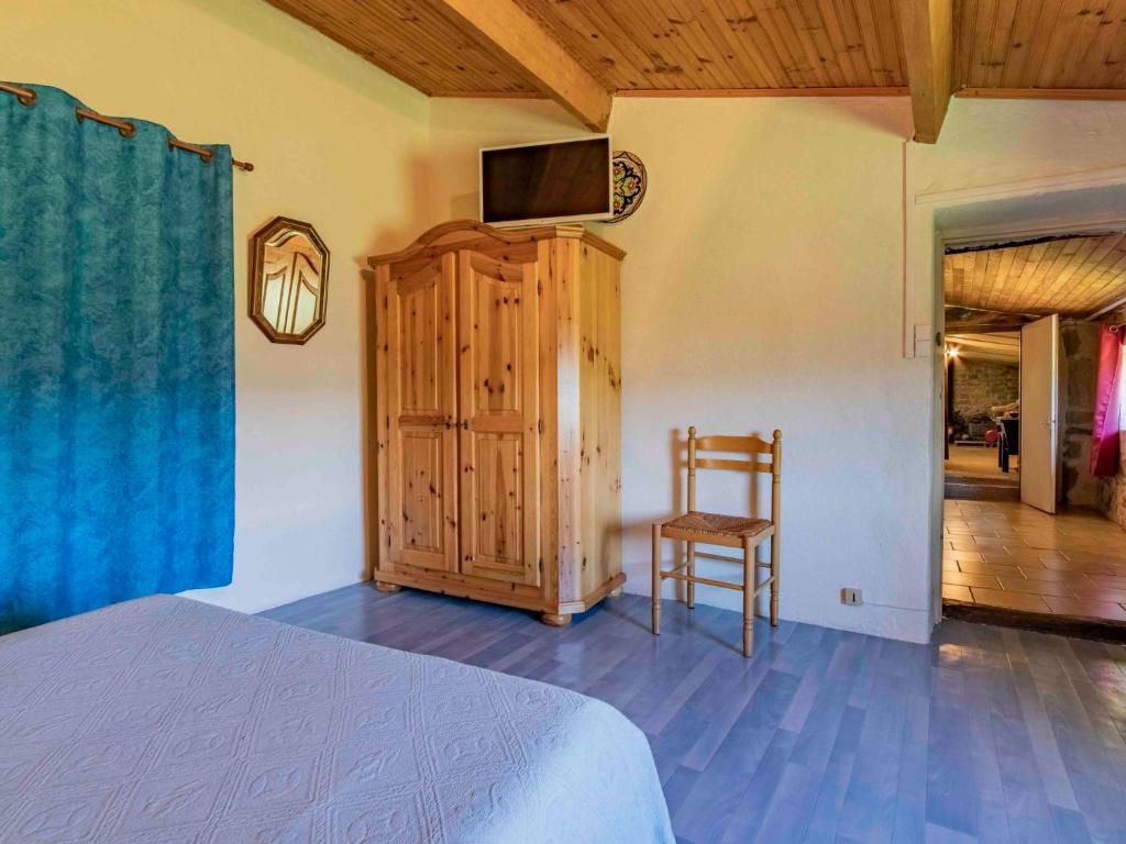 a bedroom with a bed and a tv and a chair at Holiday Home Le Cèdre - RSB100 by Interhome in Roche-Saint-Secret