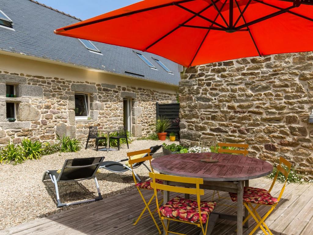 - un parasol rouge sur une terrasse en bois avec une table et des chaises dans l'établissement Holiday Home Aven by Interhome, à Trégunc