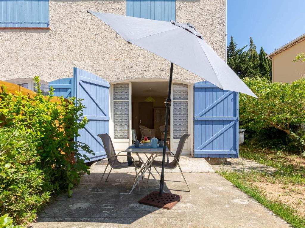une table avec un parasol devant une maison dans l'établissement Studio L'Ayguade-2 by Interhome, à Hyères