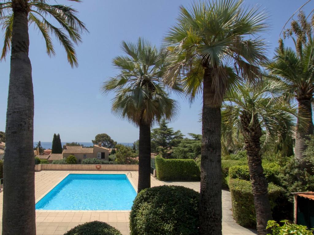 a pool surrounded by palm trees and bushes at Apartment Le Bali-2 by Interhome in La Ciotat