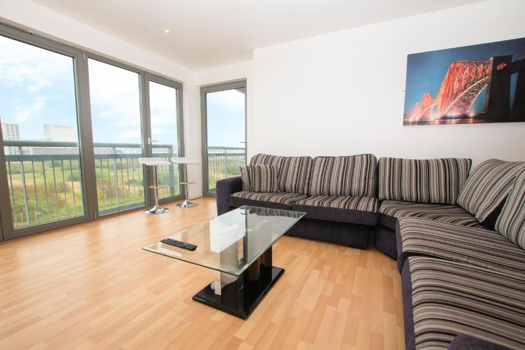 uma sala de estar com um sofá e uma mesa de vidro em Blue Harbour Apartments em Edinburgo