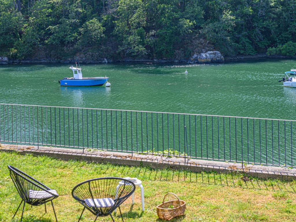 Un barco en el agua con dos sillas y un bote. en Holiday Home Glann Aven by Interhome, en Le Bono