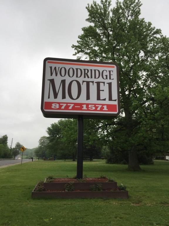 ein Schild für ein Motel mit einer Holzpatrone auf einem Feld in der Unterkunft Woodridge Motel in Terre Haute
