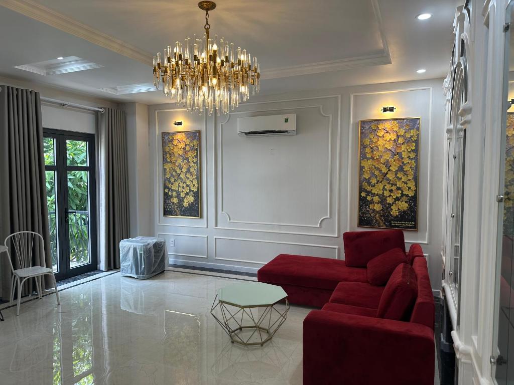 RUBY HOTEL في Tây Ninh: غرفة معيشة بها أريكة حمراء وثريا