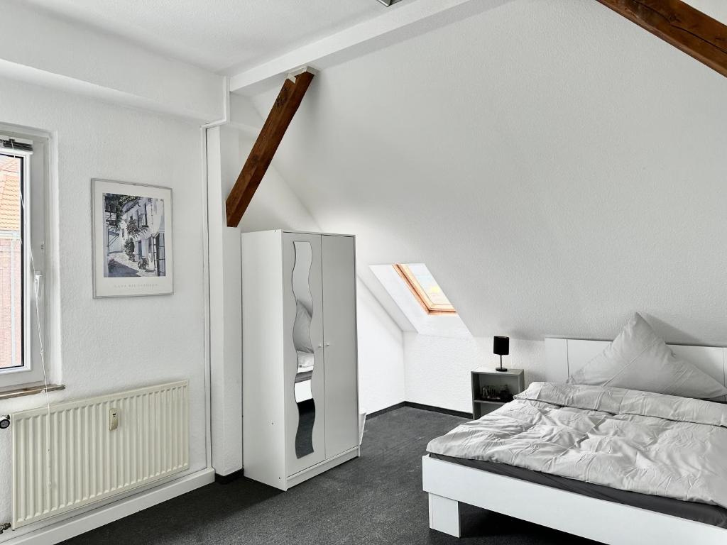 a white bedroom with a bed and a mirror at Ferienwohnung Flaming House Bitterfeld in Bitterfeld