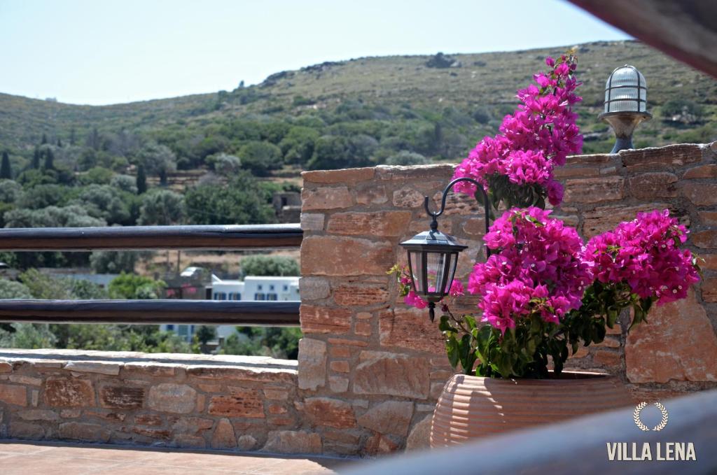 a basket of pink flowers on a wall with a lamp at VILLA LENA - ΑΝΔΡΟΣ in Batsi