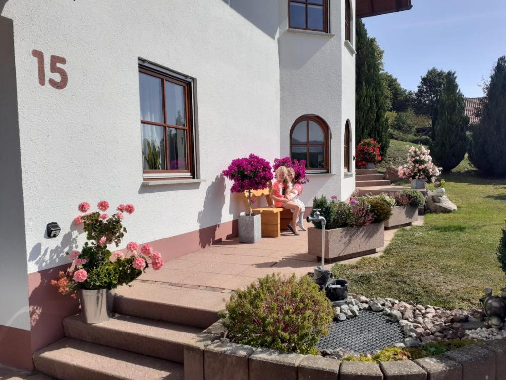 a woman sitting on the porch of a house with flowers at Mayntz' Albjuwel in Meßstetten