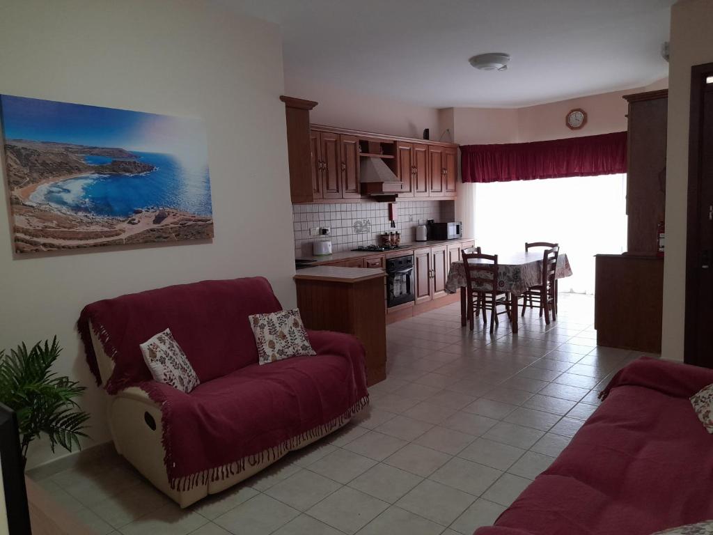 a living room with a red couch and a kitchen at Silver Shadow Holiday Maisonette in Marsaxlokk