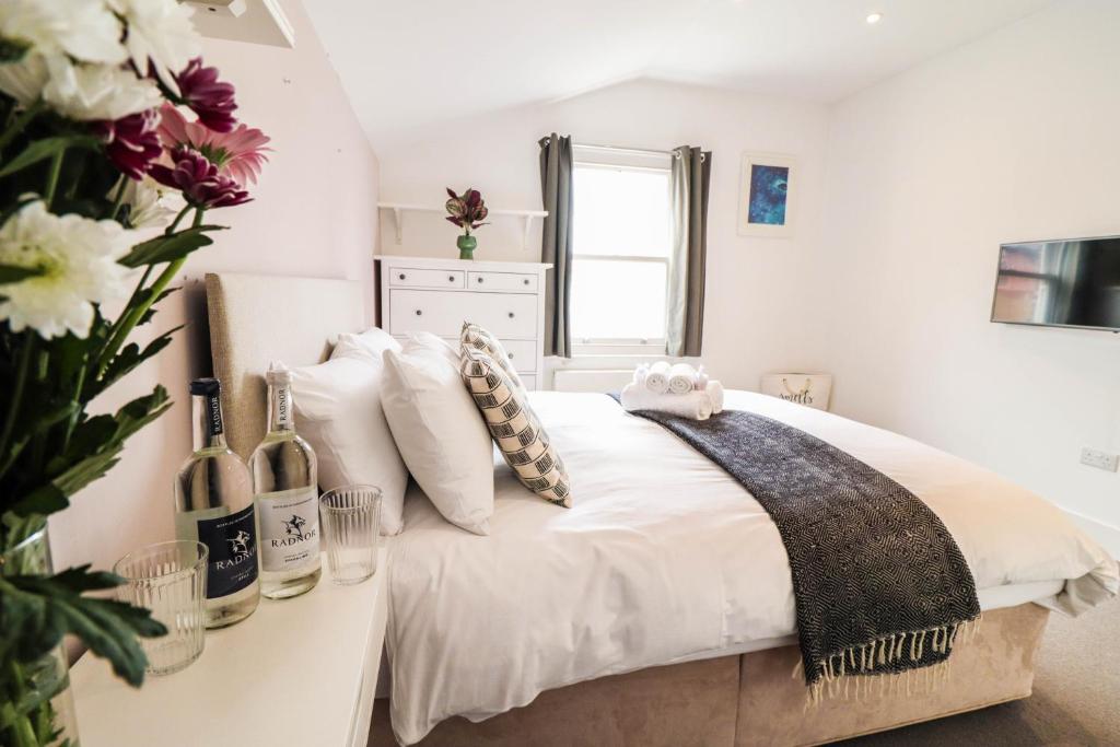 a white bedroom with a bed with a vase of flowers at Modern & spacious 1 bedroom Clapham Junction flat in London