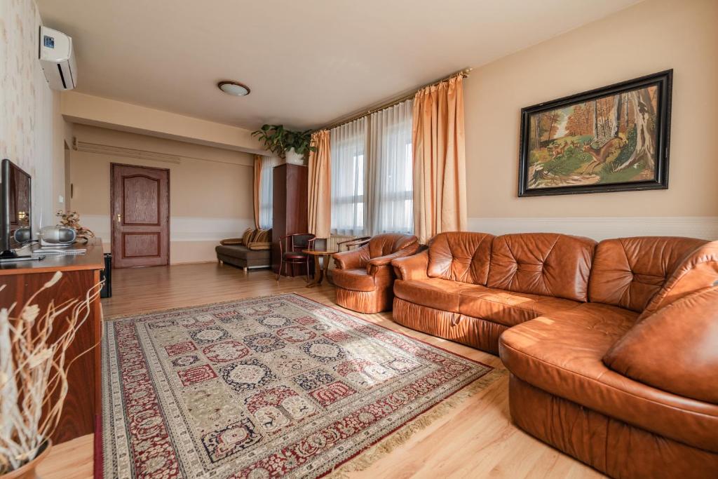 a living room with a leather couch and a rug at Panoráma Hotel in Békéscsaba