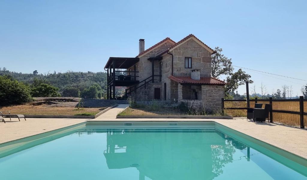 a large swimming pool in front of a house at Quinta da Adarnela in Lagares da Beira