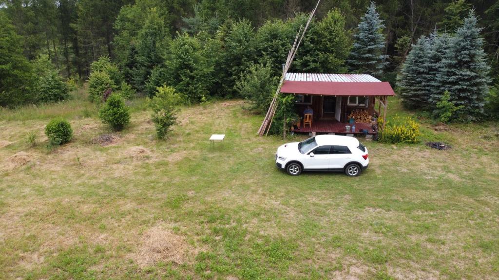 un coche blanco aparcado frente a una casa pequeña en Warmia Odludzie, en Dębiny