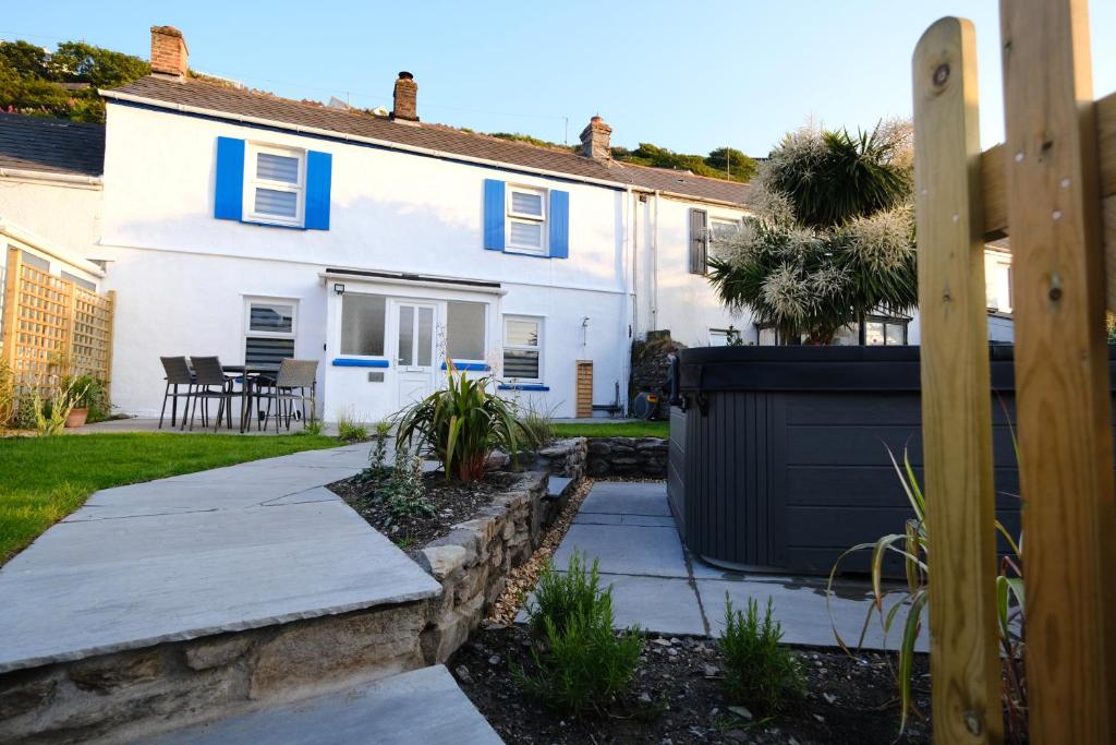 uma casa branca com persianas azuis e um quintal em Newly renovated cottage with hot tub em Portreath