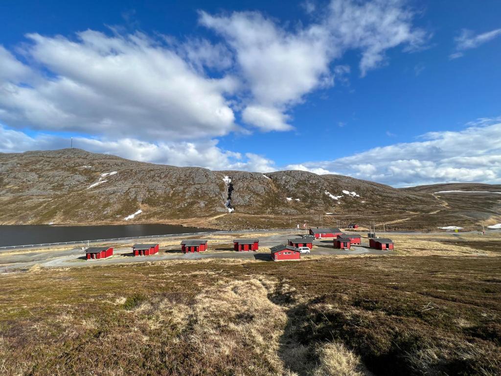 um grupo de edifícios vermelhos num campo junto a uma montanha em Hytte Camp Nordkapp - Red em Skarsvåg